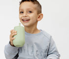 Child Holding Ezpz Happy Cup & Straw in sage - Available at www.tenlittle.com
