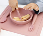 Child Holding Ezpz Happy Utensils Set of 3 in Blush - With Food Inside. Available in www.tenlittle.com