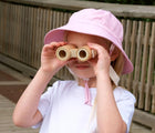 Girl looking through binoculars wearing Jan & Jul AquaDry Bucket Hat - Pink. Available at www.tenlittle.com