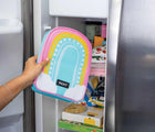 Person holding PackIt Freezable Playtime Lunch Box in rainbow next to freezer. Available from www.tenlittle.com