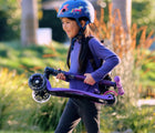 Child carrying folded Micro Kickboard Maxi Deluxe Foldable LED Scooter - Purple. Available at www.tenlittle.com