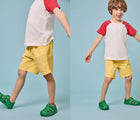 Split view of boy wearing Ten Little Splash Sandals 2 - Dino Green. Available at www.tenlittle.com